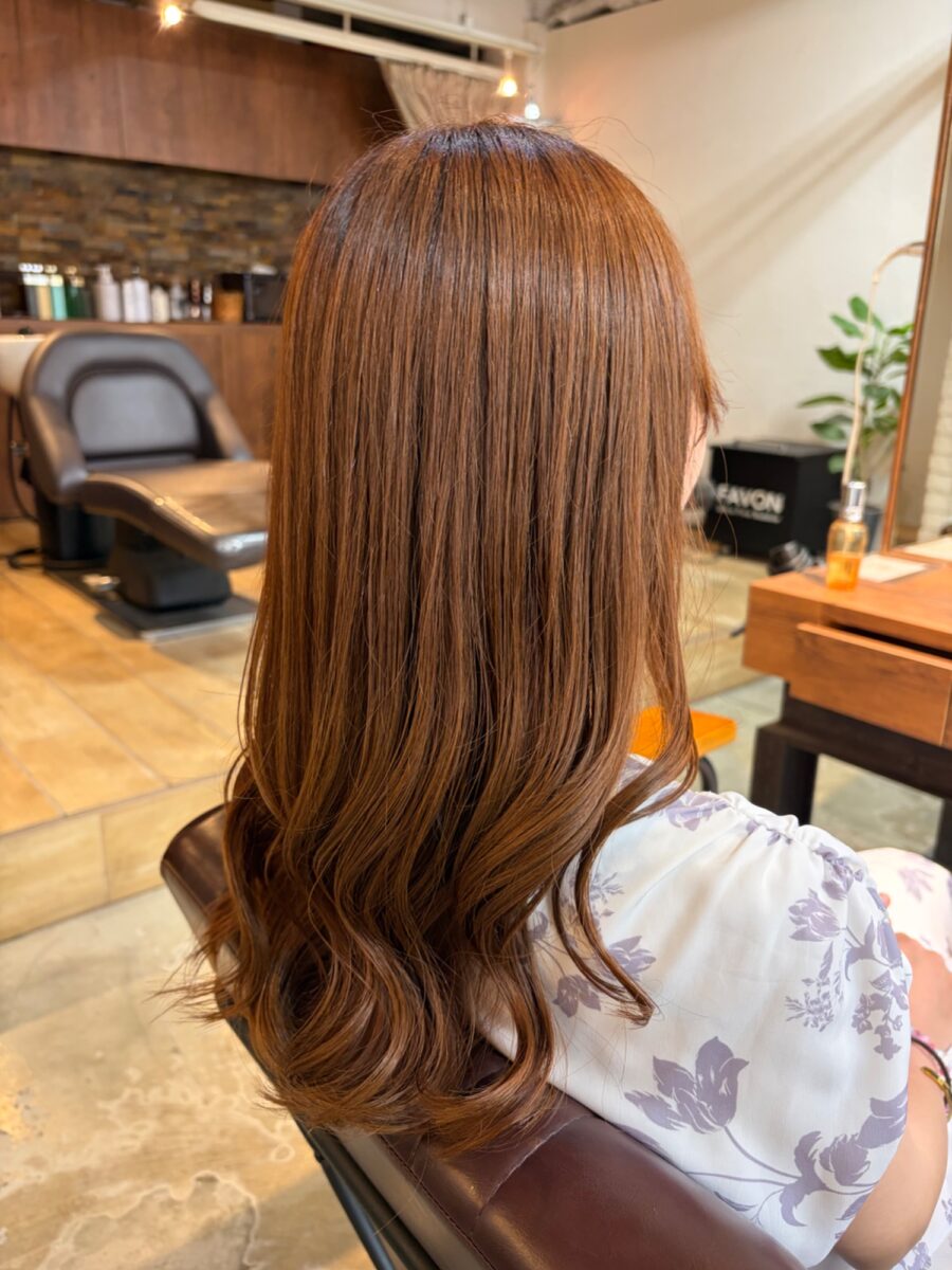 サロン内観と柔らかいウェーブがついたロングヘアの後ろ姿